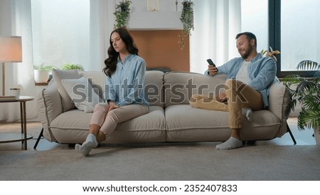 Caucasian couple at home couch sofa family problem relationship trouble offended woman girlfriend wife upset offense at husband boyfriend man addict with mobile phone social media laughing browsing