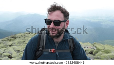 Portrait of a traveling man climbing. Tourist climber with a backpack, having a hike in the mountains, looks around. Adventure travel tourism. 4k without color correction.