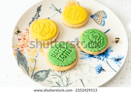 Two yellow and two green Happy Easter cookies with rabbit design lie on a designer plate, studio lighting
