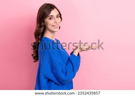 Photo portrait of attractive young woman hold palms empty space look camera wear trendy blue clothes isolated on pink color background
