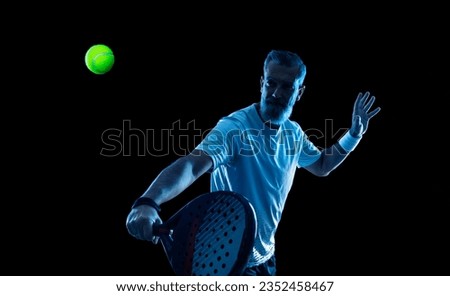 Padel tennis player with racket. Man athlete with paddle tenis racket on court with neon colors. Sport concept. Download a high quality photo for the design of a sports app or betting site.