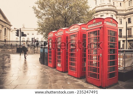 Vintage style image of typical red telephone booths on rainy street in London
