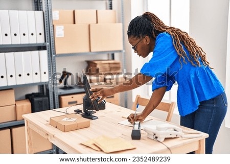 African american woman ecommerce business worker writing on notebook at street