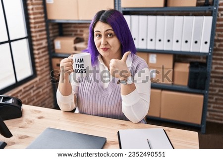 Plus size woman wit purple hair working at small business ecommerce holding i am the boss cup smiling happy and positive, thumb up doing excellent and approval sign 