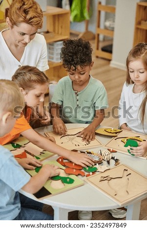 multiethnic kids and teacher playing with didactic materials in montessori school Royalty-Free Stock Photo #2352497849