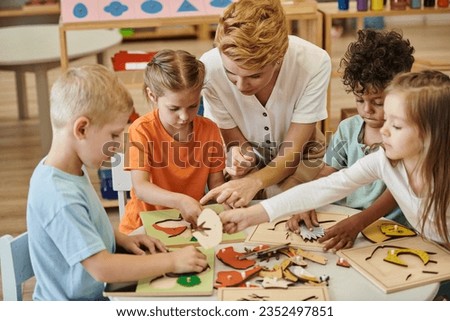 teacher playing with interracial children with didactic materials in montessori school