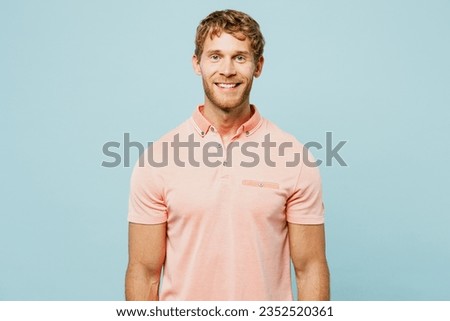 Young smiling happy satisfied positive cool cheerful caucasian blond man wear pink t-shirt casual clothes isolated on pastel plain light blue cyan color background studio portrait. Lifestyle concept