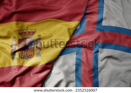 big waving national colorful flag of spain and national flag of faroe islands . macro