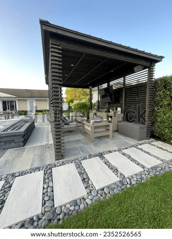 Gorgeous paving stone walkway with gray Mexican pebbles alongside pool and pavilion  pergola with pavers.  Ideal design for modern, luxury backyard living.Inspired by Tulum, Mexico's eco-chic feel. Royalty-Free Stock Photo #2352526565