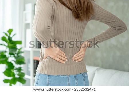Asia beautiful woman holding her lower back while and suffer from unbearable pain health and problems, chronic back pain, backache in office syndrome, scoliosis, herniated disc, muscle inflammation Royalty-Free Stock Photo #2352532471