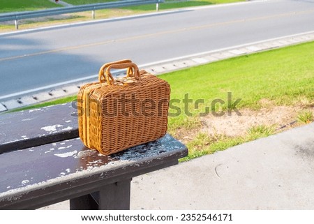 Rattan bag place on bench in outdoor for picnic day with green at park in summer,wicker basket,Fashionable handmade natural organic rattan bag.