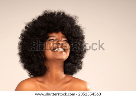 Studio portrait of young happy woman with afro hair and amazing toothy smile . Joyful girl posing in studio, expressing happiness and good mood. Happiness and real positive emotions.
