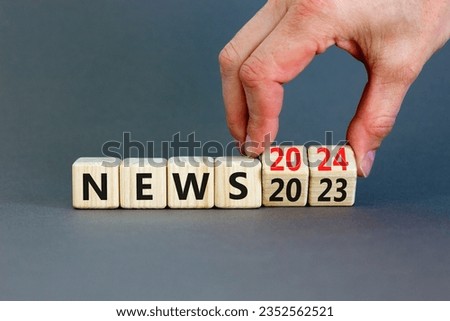 2024 News new year symbol. Businessman turns a wooden cube and changes words News 2023 to News 2024. Beautiful grey table grey background, copy space. Business 2024 news new year concept. Royalty-Free Stock Photo #2352562521
