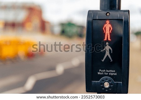 A closeup of a pedestrian crossing push button, traffic signal control with a red man symbol