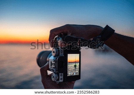 Take photos nature. Man hands holding digital camera makes photos of a sea and beautiful nature during sunset. Photographer is taking photo of summer landscape. Travel in summer, outdoor activities