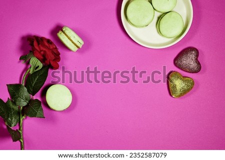 French pistachio macarons with red rose flower and  heart glitters on purple background
