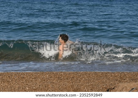 Happy little boy playing on the beach. Child run play with waves on beach