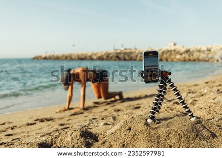 girl blogger is engaged in fitness on the seashore takes picture