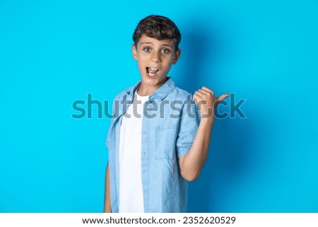 Impressed Beautiful kid boy wearing casual clothes point back empty space
