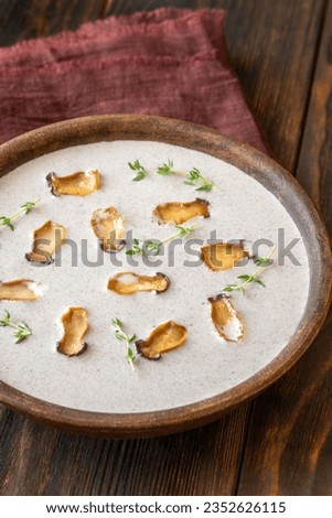 Bowl of mushroom cream soup garnished with eryngii 