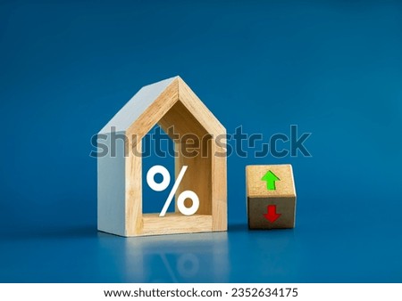 Home tax concept. Resident rate, real estate, property and building annual taxation. Big percentage icon in modern white wooden house model and up and down arrow on flip wood block on blue background. Royalty-Free Stock Photo #2352634175