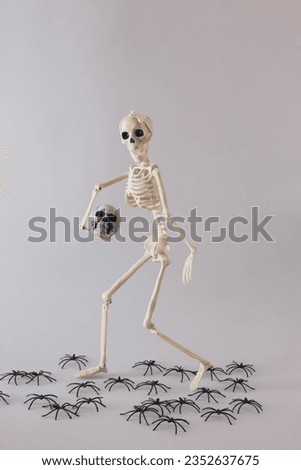 Skeleton of a woman carries the skull of a man in her hand. Creative Halloween minimal concept. Minimal horror wallpaper. 31th October party invitation card with copy space.