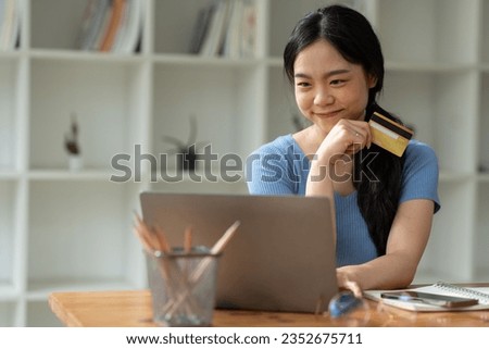 Young Asian woman using credit card and mobile phone transaction for online shopping with laptop browsing. online payment concept