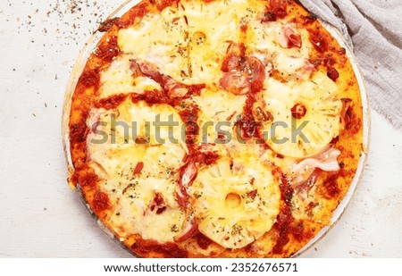 Tropical Hawaiian pizza with pineapple slices and ham on a board on a white background, top view.

