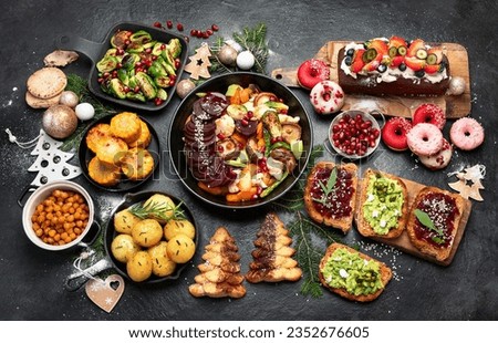 Vegan food with brussels sprouts, carrots, cauliflower, mushrooms, avocado, cake on a dark background, top view. Vegetarian Christmas dinner, healthy food. Royalty-Free Stock Photo #2352676605