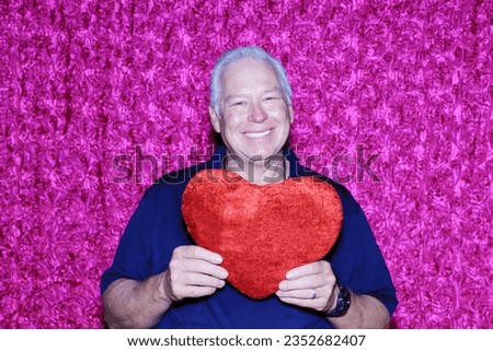 Valentines Day. Photo Booth. A man holds Red Heart and Smiles as he has his photo taken in a Valentines Day Photo Booth. Photo Booths are Fun for All Holidays. Valentines day Picture Booth. Love. 