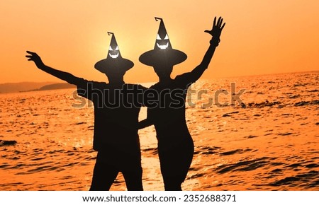 Witch Hat Halloween costume love couple at Sunset: Silhouette Lover Celebrating Outdoors in Costume over glowing light effect halloween hat.