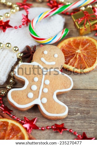 Homemade christmas painted gingerbreads (gingerbread man and red boot) on the wooden background with Christmas decorations, cones and candied orange. Selective focus on face. Toned