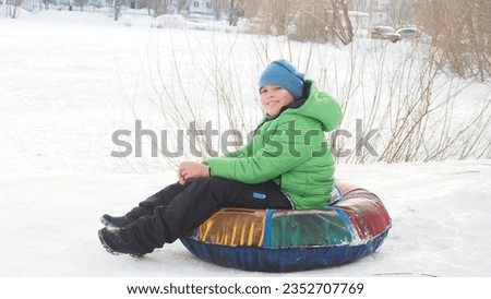 Active toddler school boy sliding down the hill on snow tube. Happy children, siblings having fun outdoors in winter on sledge. child tubing snowy downhill, family time. outdoor winter active sport.