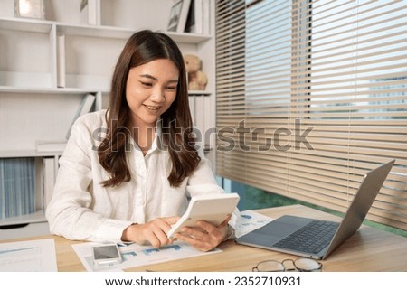 Asian woman working at office, Press calculator, Calculate the income - expenses, Use the laptop to record the information and check the accuracy.