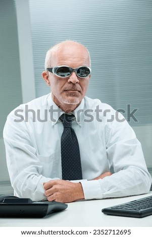 In his office, a man dons biker sunglasses, exuding exaggerated confidence at his desk. Believing he's the ultimate boss and solver, he feels no need for a team. Senior businessman in white shirt and 