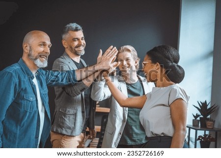 Unity and teamwork within a business setting. A diverse multi ethnical group of freelancers or businessmen gather in a loft office, their faces radiating camaraderie and positivity. . High quality Royalty-Free Stock Photo #2352726169
