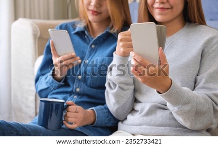 Closeup image of a young couple women using and looking at mobile phone together