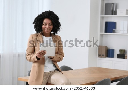 Smiling young businesswoman using tablet in modern office