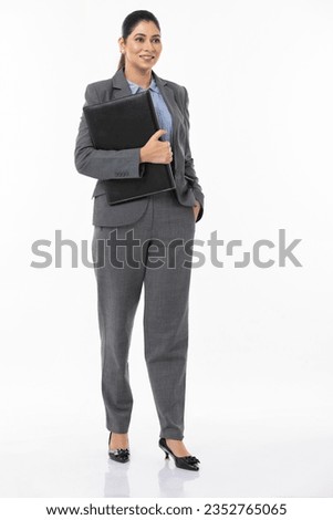Young businesswoman holding file against white background.