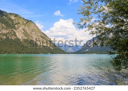View over the lake Heiterwanger See near Heiterwang in Austria on a sunny day with blue sky and cumulus clouds. Royalty-Free Stock Photo #2352765427