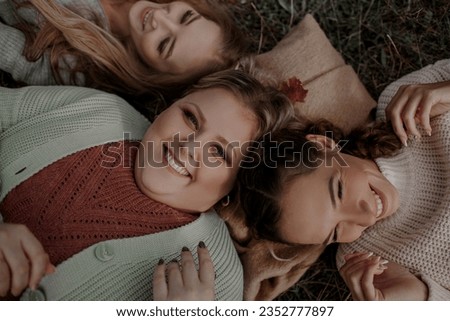 Multiracial female people  with different bodies and hairs walking in the fall parks together.  Friends wearing warm fashion clothes, knitted sweaters.  Royalty-Free Stock Photo #2352777897