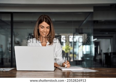 Middle-age Hispanic woman using laptop computer for business studying, watch online virtual webinar training meeting,video call. Focused mature 40s years Latin businesswoman work in office, copy space Royalty-Free Stock Photo #2352826913