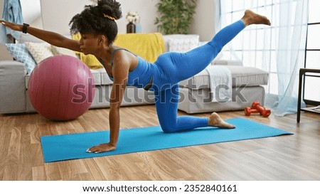 African american woman wearing sportswear stretching back at home Royalty-Free Stock Photo #2352840161