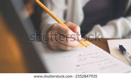 No face closeup hand young adult women writing note for study and work online. Workplace table with laptop computer. University people city lifestyle on day concept. Royalty-Free Stock Photo #2352847935