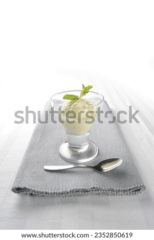 one scoop of premium vanilla ice cream dessert with mint leaf in cocktail glass spoon on grey cloth white table asian dessert cuisine halal food restaurant menu for cafe