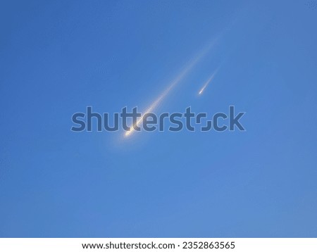 Fall of meteorites during the day. Meteors against the blue sky. Fireballs in the light of the sun.