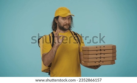 Delivery man with portable backpack refrigerator holding stack of pizza boxes and shows ok sign. Isolated on blue background.