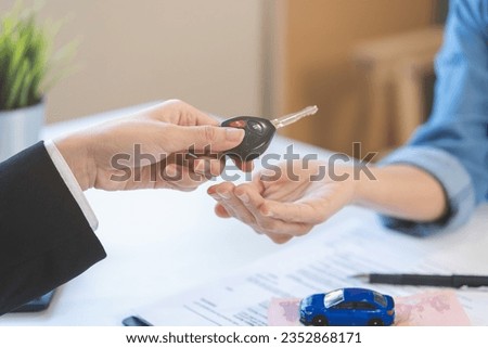 Business car rental company service, Close up hand of agent dealer giving, holding car key to customer renter, new owner after signed rental, purchase contract in document, vehicle sales agreement.