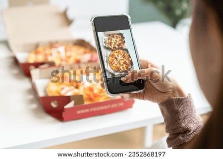 Happy meal, enjoy eating beautiful asian young woman taking photo of pizza in box by mobile smart phone on table at home before eat fast or junk food, post picture to communication on social networks.