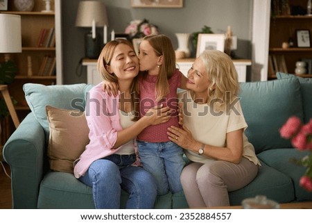 Three female generation portrait. Little girl kissing her mother